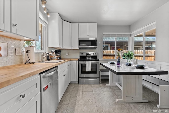 kitchen with a sink, white cabinets, a wealth of natural light, and stainless steel appliances