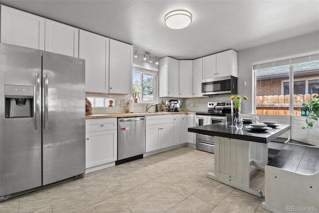 kitchen with a sink, appliances with stainless steel finishes, tasteful backsplash, and white cabinetry
