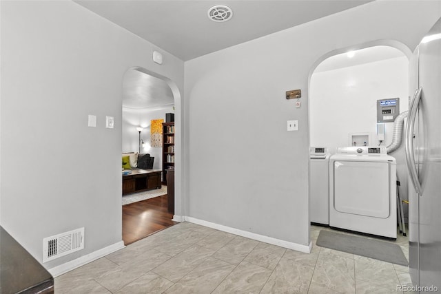 clothes washing area featuring arched walkways, baseboards, washing machine and dryer, and visible vents
