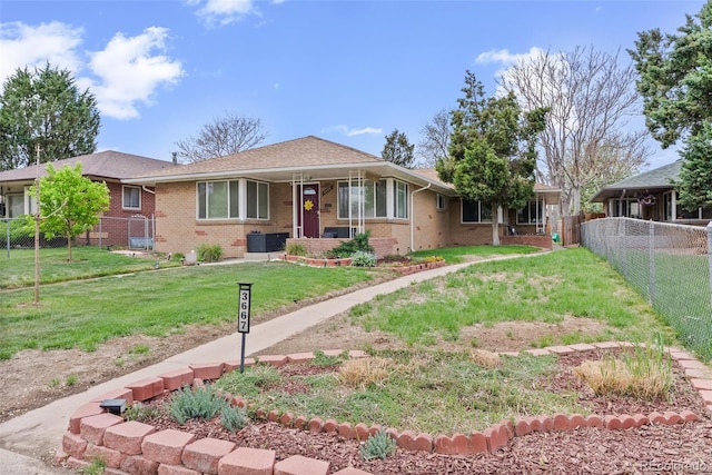 view of front of property featuring brick siding, central AC, fence, and a front lawn