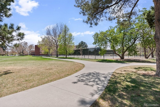 view of property's community featuring a lawn and fence