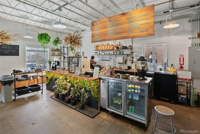 bar with concrete block wall, a bar, concrete flooring, and beverage cooler