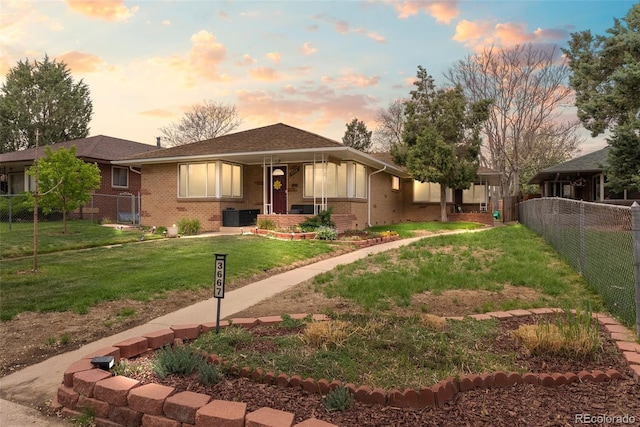 view of front facade with brick siding, a front lawn, fence, and a porch