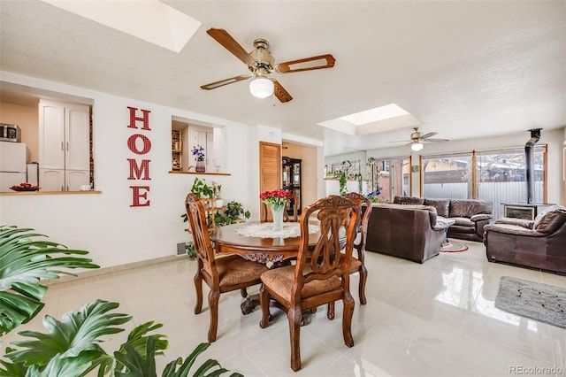 tiled dining area with a skylight, ceiling fan, and a textured ceiling