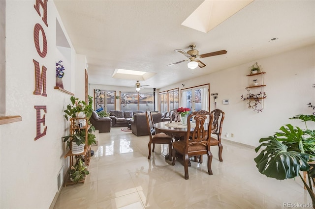 dining area with ceiling fan and a skylight