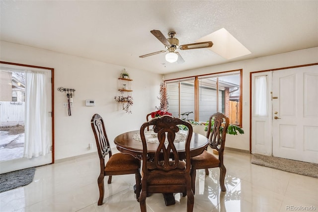 dining space with a skylight, ceiling fan, and a textured ceiling