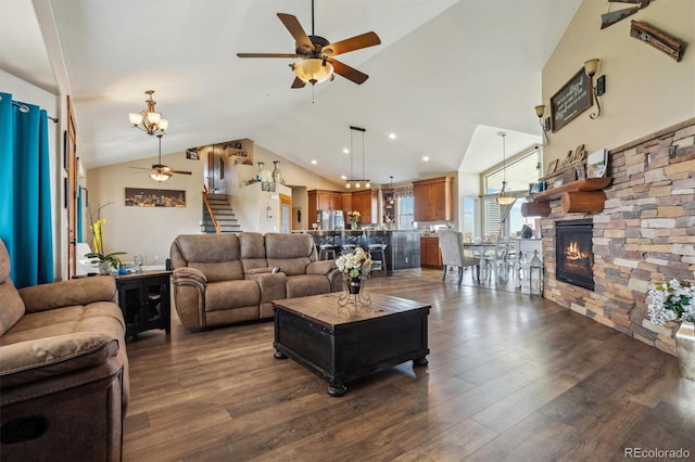 living room featuring lofted ceiling, ceiling fan with notable chandelier, a stone fireplace, and dark hardwood / wood-style floors