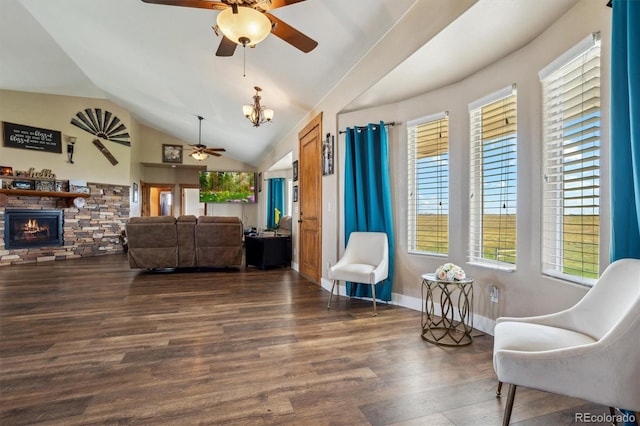 living room with a stone fireplace, ceiling fan with notable chandelier, dark hardwood / wood-style floors, and vaulted ceiling