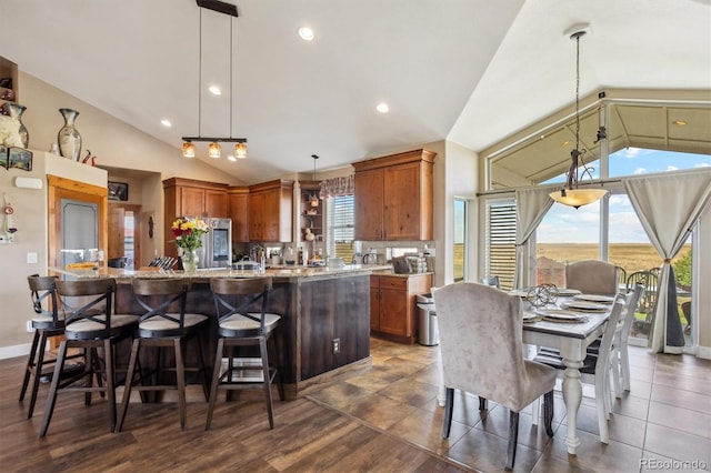 kitchen with stainless steel fridge, decorative light fixtures, dark hardwood / wood-style floors, and plenty of natural light