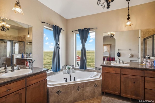 bathroom featuring plus walk in shower, a notable chandelier, plenty of natural light, and vanity