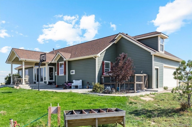 rear view of property featuring a yard, a garage, and a patio area