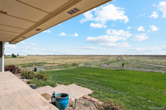 view of yard with a rural view and a patio area