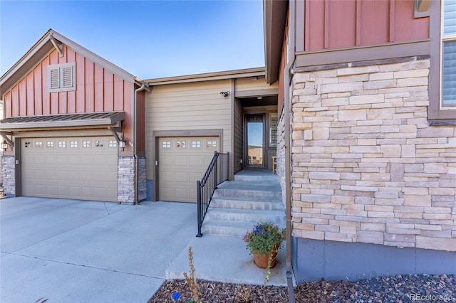 view of front of home with driveway, stone siding, an attached garage, and board and batten siding