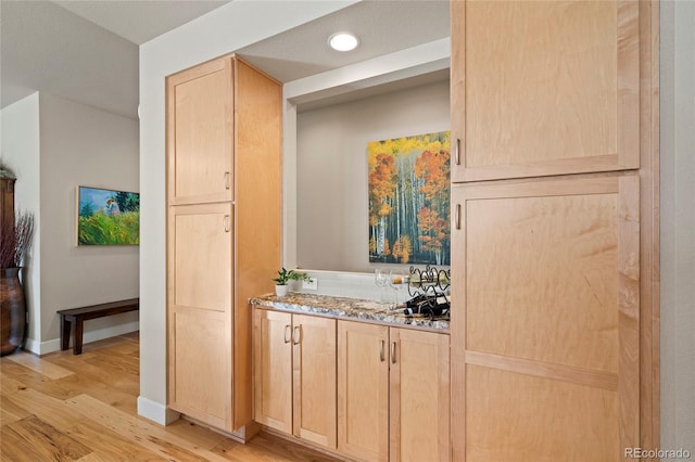 kitchen with stone counters, light brown cabinets, light wood-style flooring, recessed lighting, and baseboards