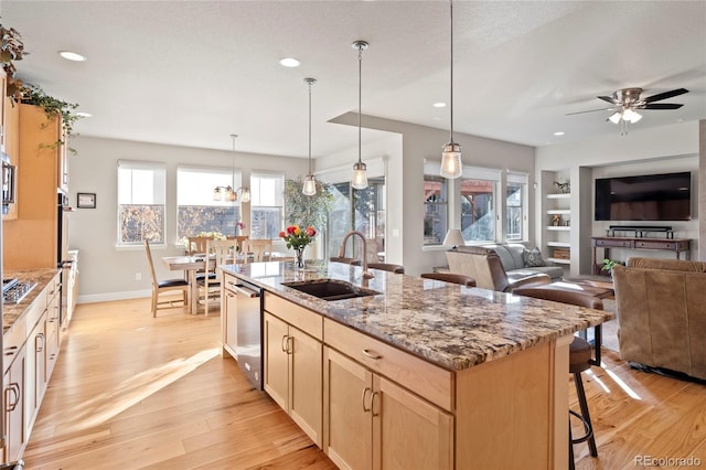 kitchen with light wood-style floors, a kitchen bar, light brown cabinets, and a sink