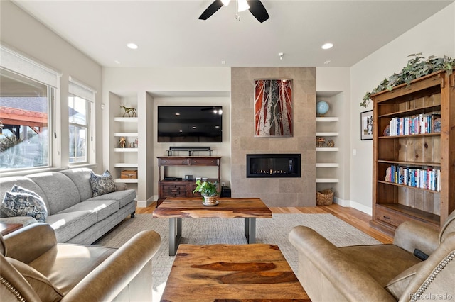 living area with built in features, a fireplace, recessed lighting, wood finished floors, and baseboards