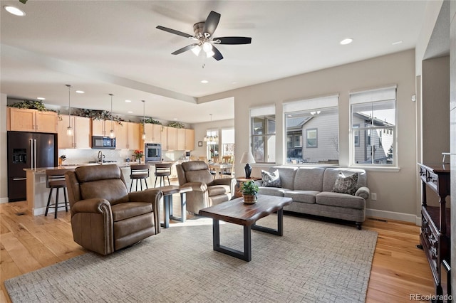 living area with recessed lighting, ceiling fan, light wood-style flooring, and baseboards