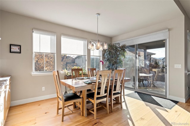 dining room with light wood-style flooring, baseboards, and a chandelier