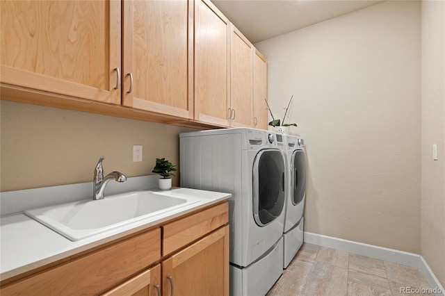 laundry room with washing machine and dryer, cabinet space, a sink, and baseboards