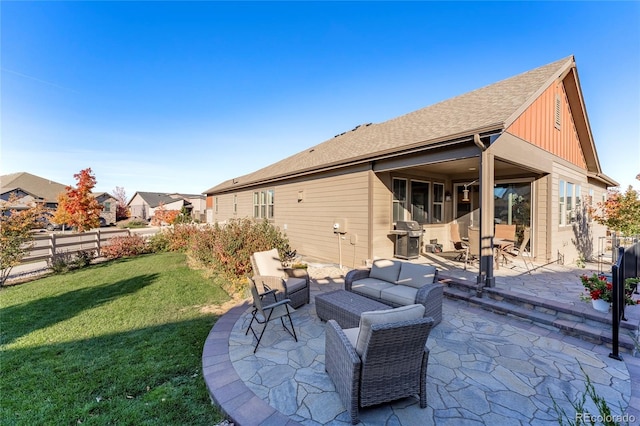 back of property with a shingled roof, a patio, an outdoor hangout area, fence, and a yard