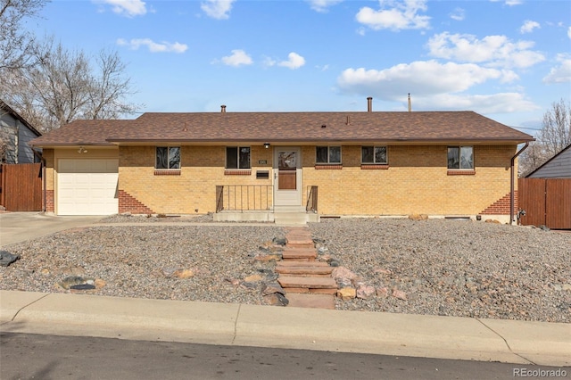 single story home featuring brick siding, concrete driveway, a garage, and fence