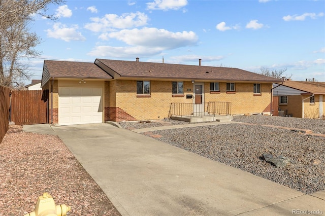 ranch-style house featuring fence, roof with shingles, an attached garage, concrete driveway, and brick siding