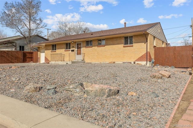 ranch-style home featuring fence and brick siding