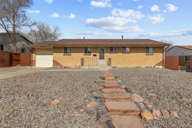 single story home featuring brick siding, concrete driveway, an attached garage, and fence