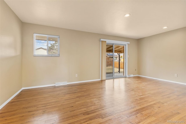 unfurnished room with light wood-style flooring, a healthy amount of sunlight, visible vents, and baseboards