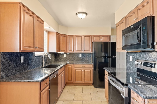 kitchen featuring black appliances, a sink, dark stone countertops, light tile patterned floors, and decorative backsplash