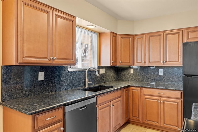 kitchen featuring light tile patterned floors, freestanding refrigerator, a sink, decorative backsplash, and stainless steel dishwasher