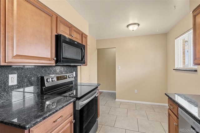 kitchen featuring dark stone countertops, stainless steel appliances, baseboards, and decorative backsplash