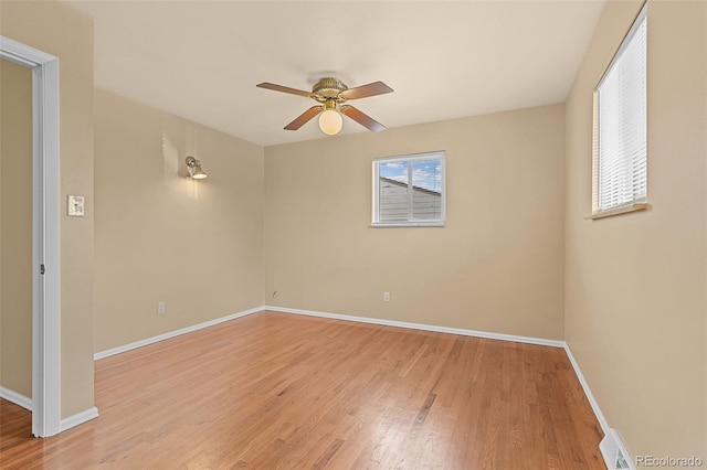 empty room featuring a wealth of natural light, baseboards, light wood-style floors, and a ceiling fan