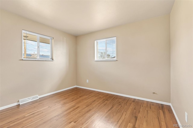 spare room featuring wood finished floors, visible vents, and baseboards