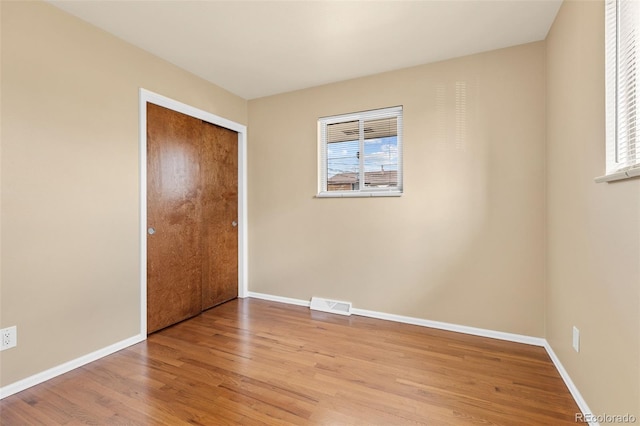 unfurnished bedroom with visible vents, baseboards, a closet, and wood finished floors