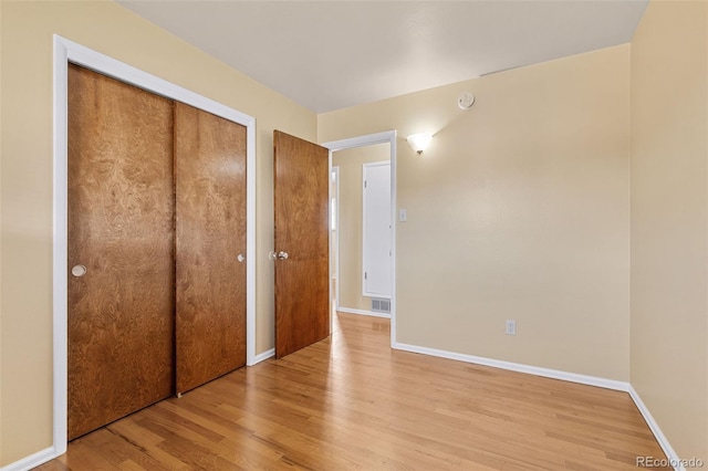 unfurnished bedroom featuring light wood-style floors, visible vents, a closet, and baseboards