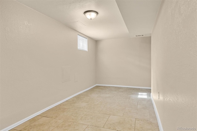 unfurnished room with light tile patterned floors, visible vents, baseboards, and a textured wall