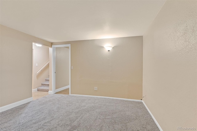 finished basement with baseboards, light carpet, and stairs