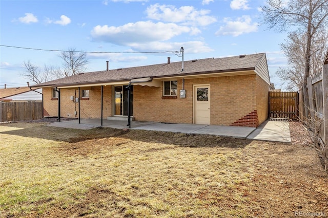 rear view of property with a patio, a yard, a fenced backyard, and brick siding