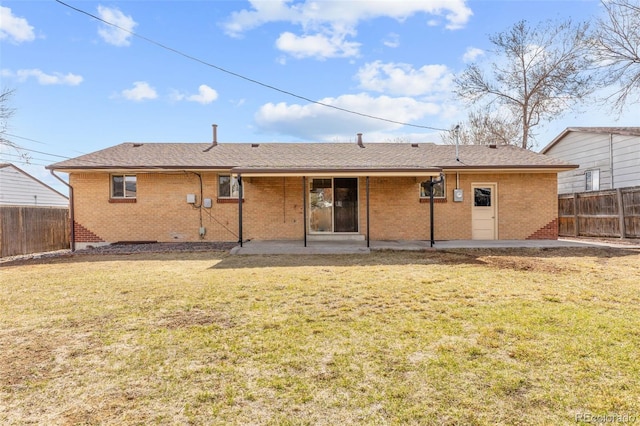 rear view of property featuring a patio, a lawn, a fenced backyard, and brick siding