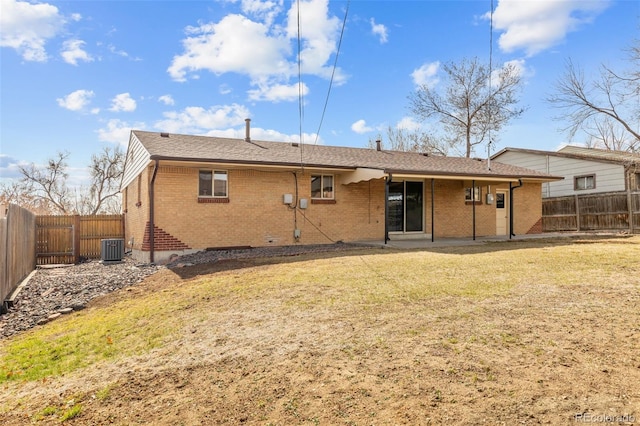 rear view of property with brick siding, central air condition unit, a yard, and a fenced backyard