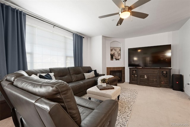 living room with ceiling fan, light carpet, and a tiled fireplace