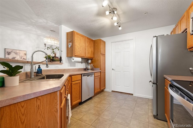 kitchen featuring sink, a textured ceiling, light tile patterned floors, and appliances with stainless steel finishes