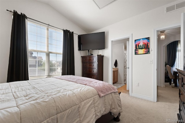 bedroom featuring vaulted ceiling, connected bathroom, and light carpet