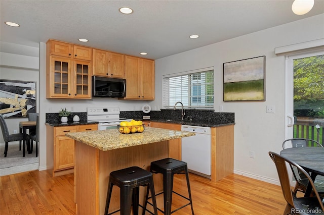 2500 Lexington St, Lafayette, CO 80026 - kitchen with white appliances, a sink, light wood-type flooring, a breakfast bar, and recessed lighting