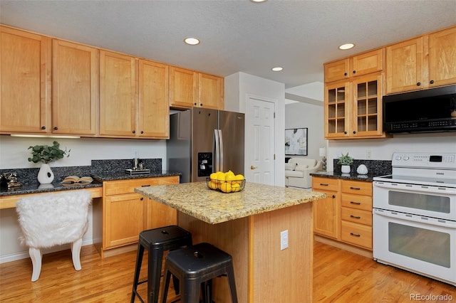 2500 Lexington St, Lafayette, CO 80026 - kitchen featuring black microwave, range with two ovens, stainless steel refrigerator with ice dispenser, light wood finished floors, and a kitchen bar