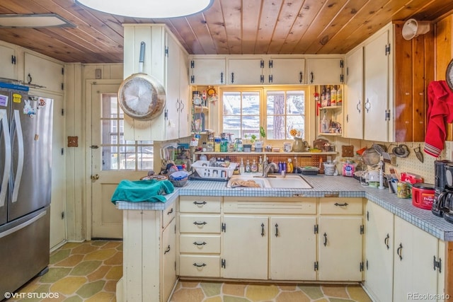 kitchen featuring stainless steel fridge, wood ceiling, and sink