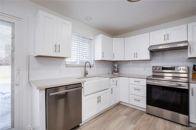 kitchen with stainless steel appliances, white cabinets, under cabinet range hood, and light wood finished floors