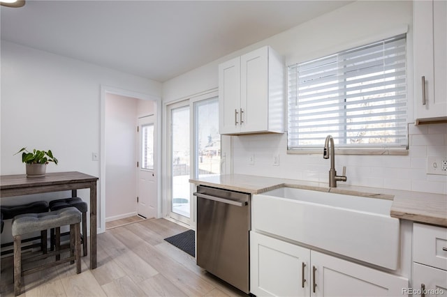 kitchen with stainless steel dishwasher, decorative backsplash, a sink, and white cabinets