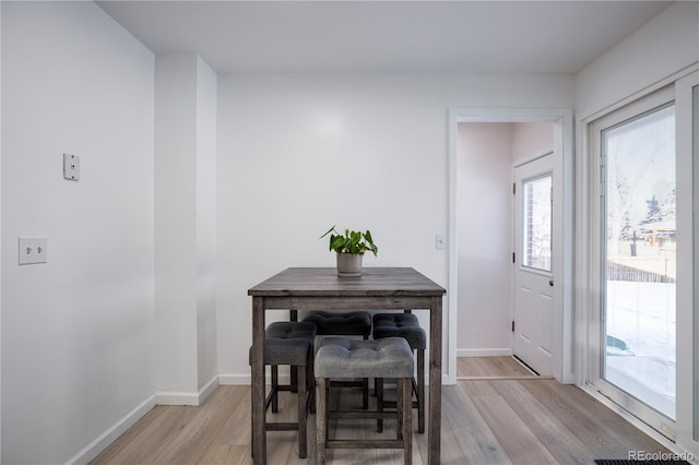 dining space featuring light wood-type flooring and baseboards